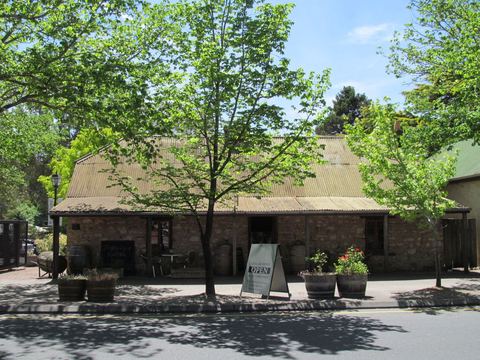A stone building with a corrugated roof set among garden trees