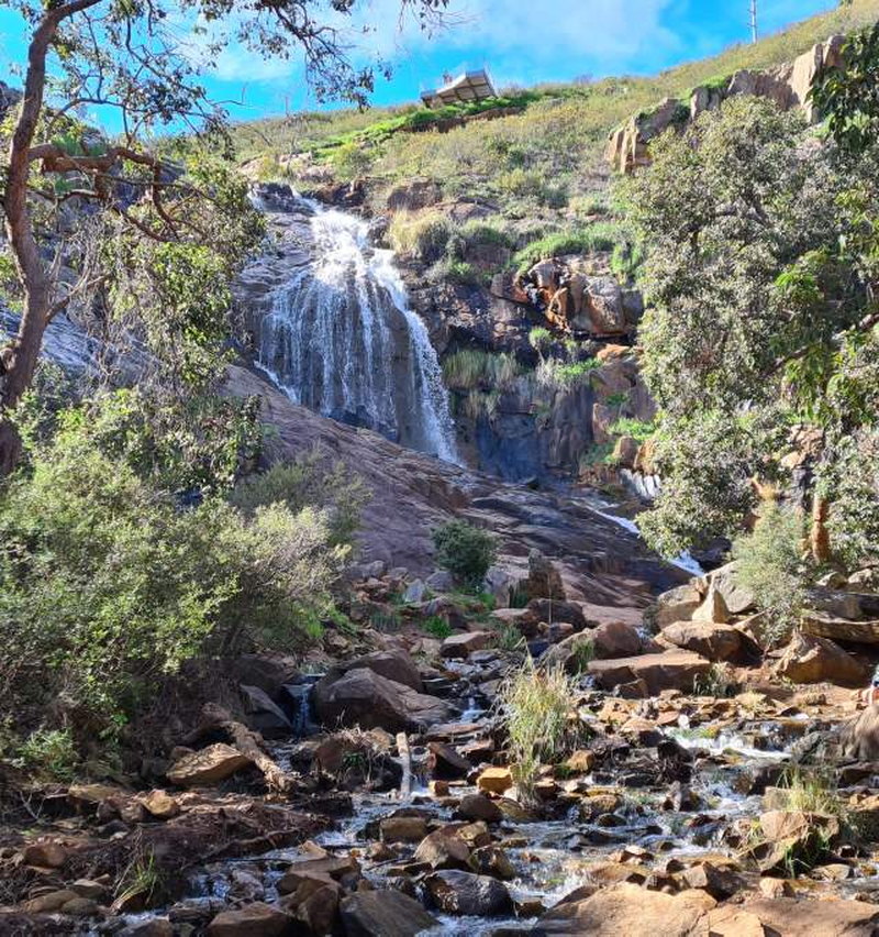 A waterfall cascading over a rocky hillside into a shallow stream