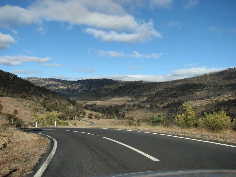 A sealed road curving through open, grassy high country